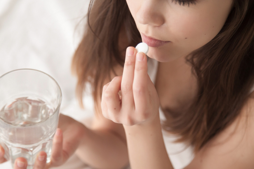 woman taking pill to help sleep.