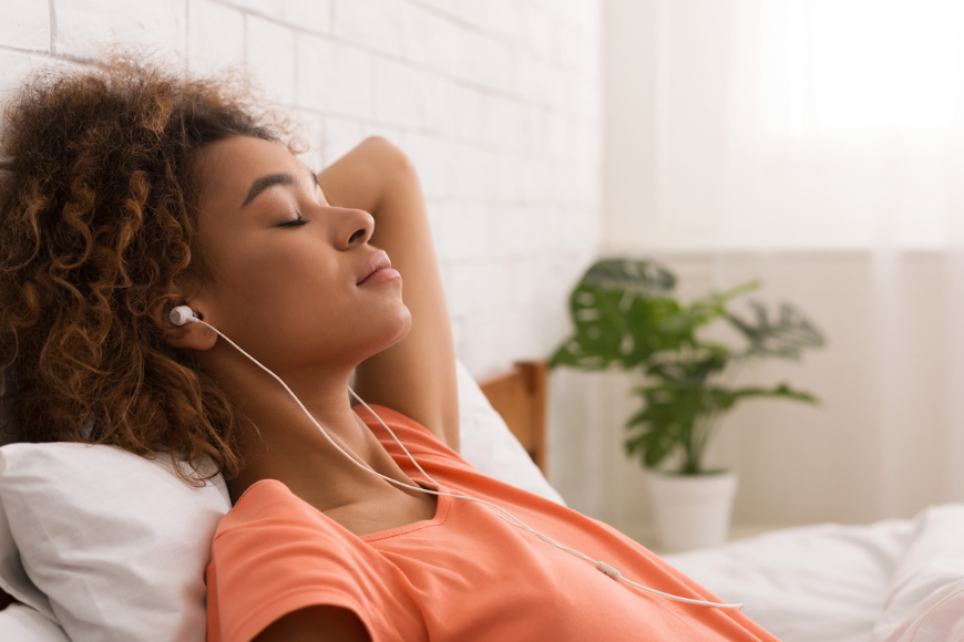 young woman with earbuds eyes closed.