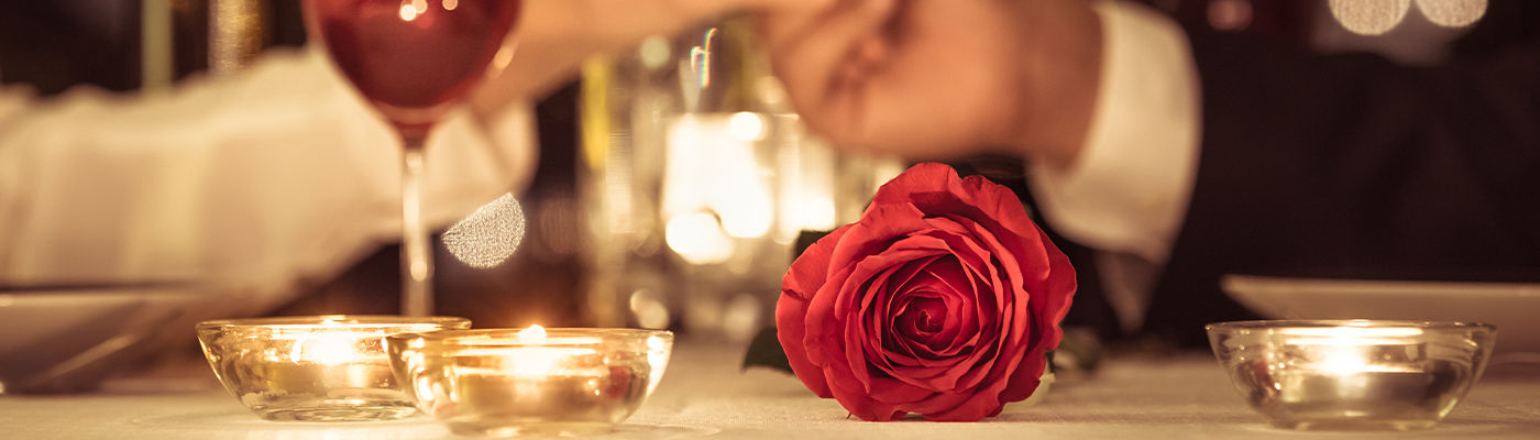 Couple holding hands across candlelit dinner table