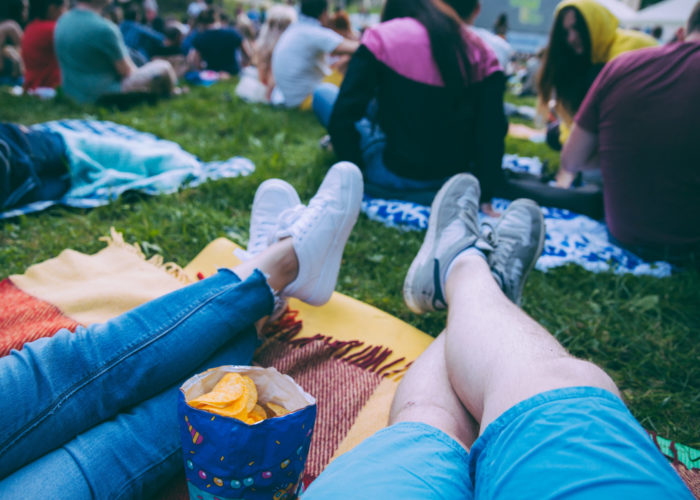 Two sets of legs resting on an outdoor blanket in a crowd