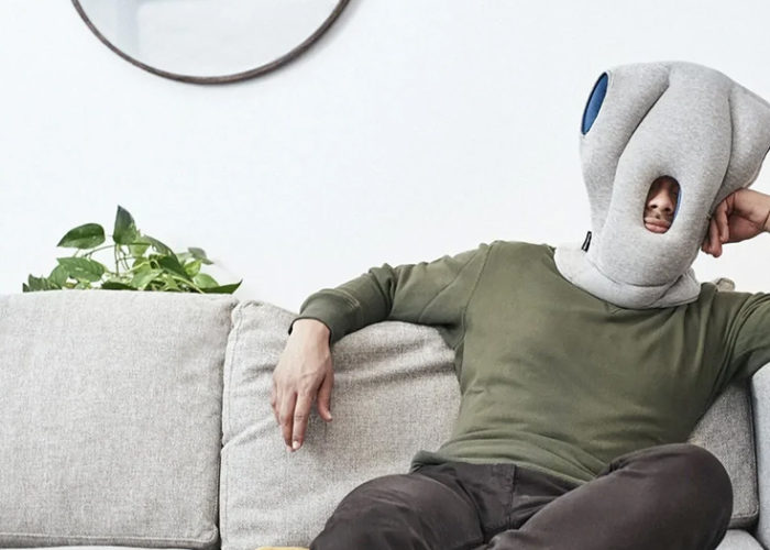 Man wearing an Ostrichpillow and lounging on a couch