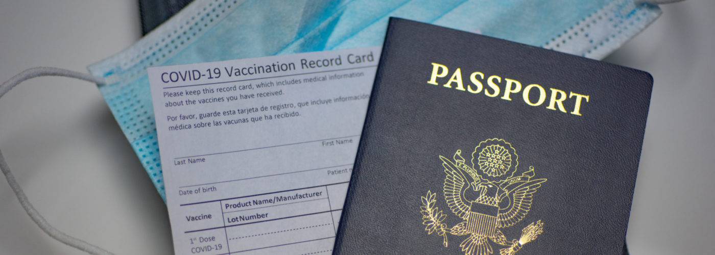 Passport, face mask, and vaccine card on table