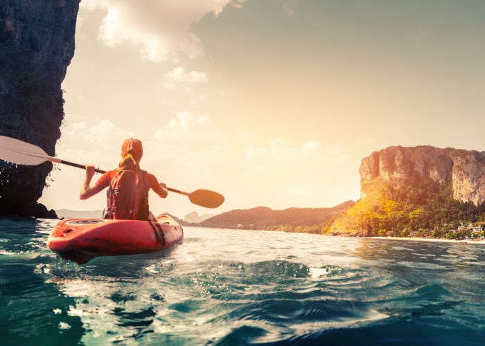 Woman kayaking in a canyon at sunset