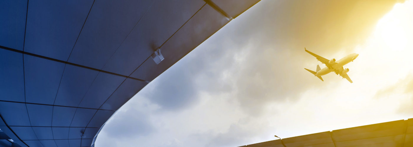 Plane flying over the passenger drop off area of an airport