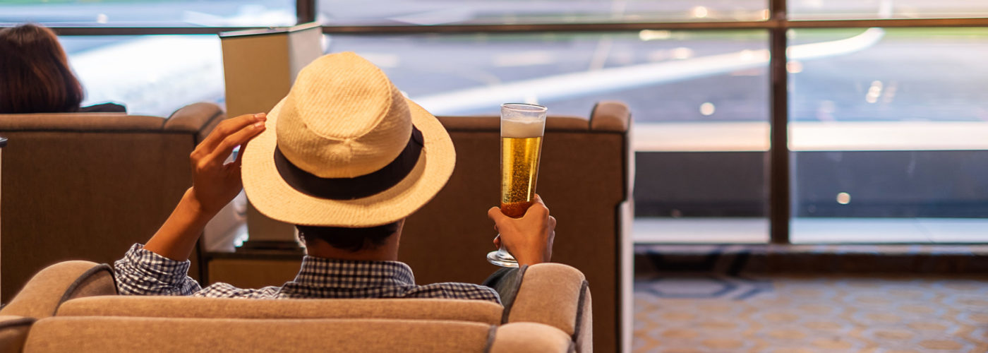 Man holding a full glass of beer in an airport terminal