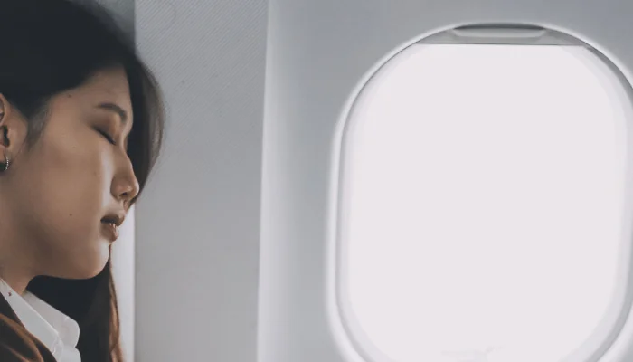 Photo of woman sitting on an airplane trying to sleep