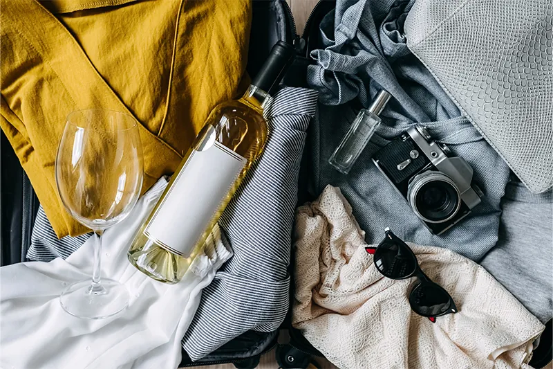 Bottle of wine amongst travel clothes and a camera